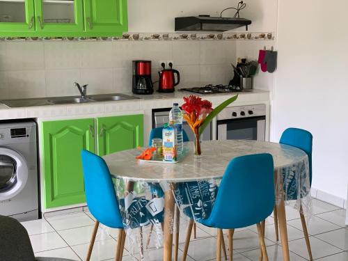 een keuken met groene kastjes en een tafel met blauwe stoelen bij Les Lianes De Jade in Deshaies