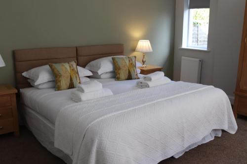 a bedroom with a large bed with white sheets and a window at The New Inn in Fife