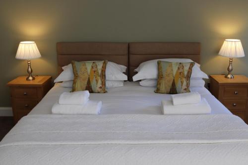 - un grand lit blanc avec deux lampes de chaque côté dans l'établissement The New Inn, à Fife