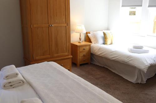 - une chambre avec 2 lits et une armoire en bois dans l'établissement The New Inn, à Fife