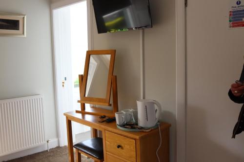 a wooden dresser with a mirror and a television on it at The New Inn in Fife