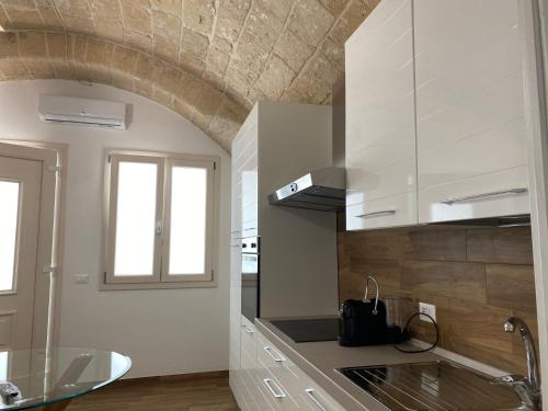 a kitchen with white cabinets and a window at La Maison dello zio in Monopoli