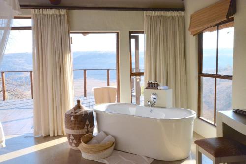 a bathroom with a large tub in front of windows at Esiweni Luxury Safari Lodge in Nambiti Private Game Reserve