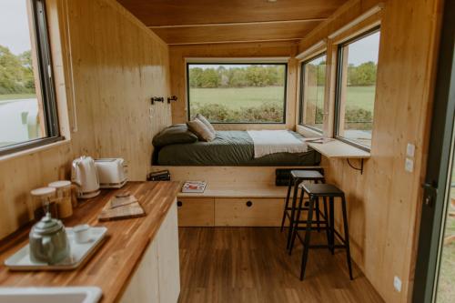 Cette petite maison comprend un lit et une cuisine. dans l'établissement Parcel Tiny House I Ferme de Garance, à Magnac-Laval