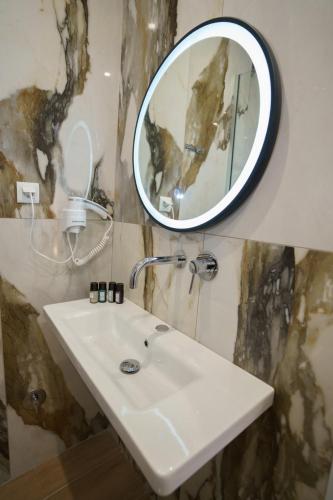 a bathroom with a white sink and a mirror at Eleni Studios Parga in Parga