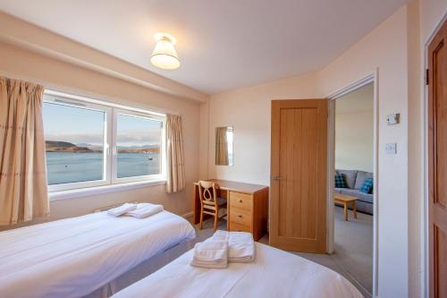 a bedroom with a bed and a desk and a window at Esplanade Court Holiday Apartments in Oban