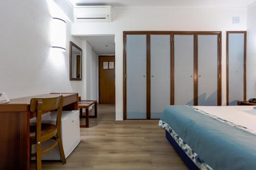 a room with a bed and a desk and a table at Hotel Arangues in Setúbal