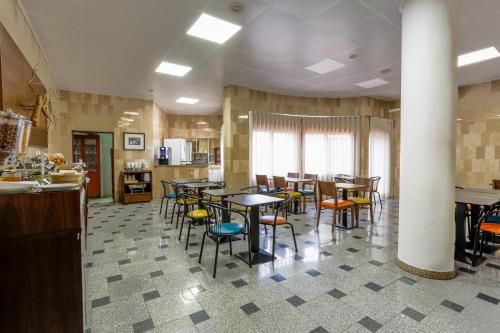 a restaurant with tables and chairs in a room at Hotel Arangues in Setúbal
