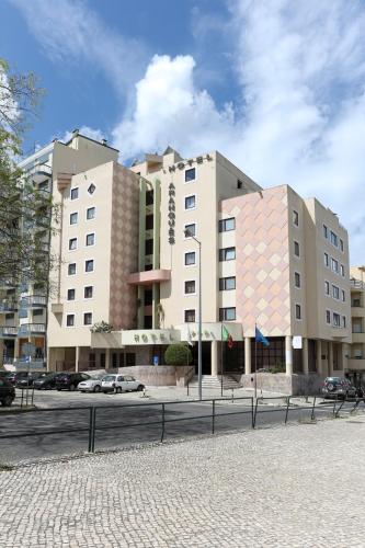 a large building with cars parked in front of it at Hotel Arangues in Setúbal