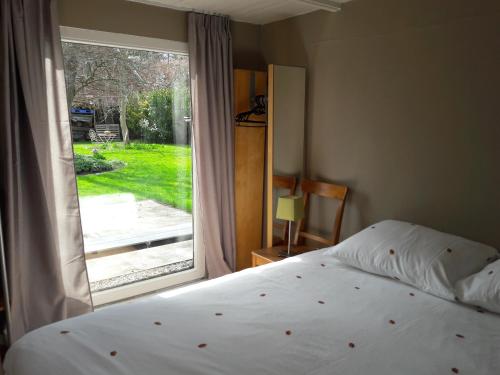 a bedroom with a bed and a large window at B&B 't Gezellig Huizeke in Zoersel