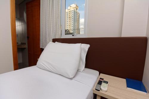 a bed with a white pillow on top of it at Fênix Hotel Moema in São Paulo