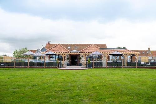 a house with a grass field in front of it at Briarfields Hotel in Titchwell
