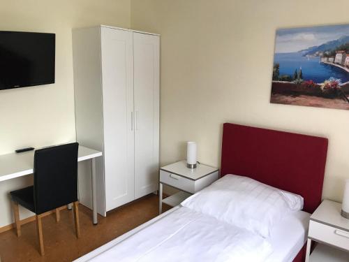 a bedroom with a bed and a desk and a tv at Hotel Garni Elisabeth in Göppingen