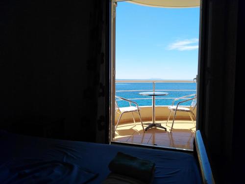 a bedroom with a view of the ocean from a balcony at Magic Ionian Apartments & Rooms in Himare