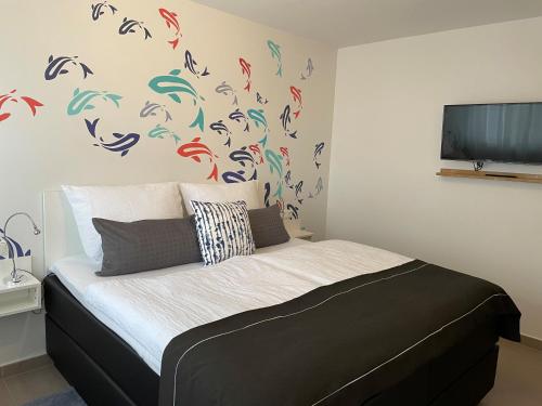 a bedroom with a bed with colorful birds on the wall at Appartementanlage Lancken-Granitz in Lancken-Granitz