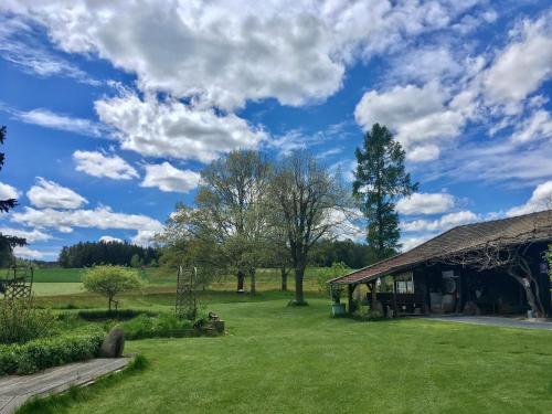 a barn in a field with a blue sky and clouds at Familienapartments mit Balkon oder Terrasse und Garten in Ober-Lembach