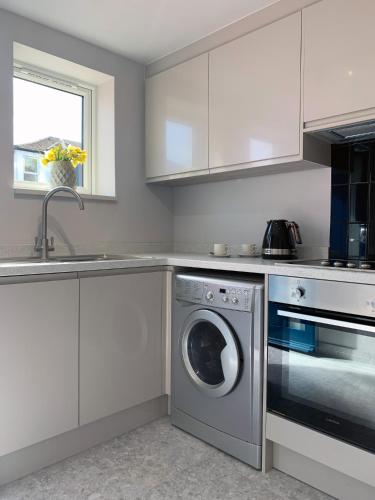 a kitchen with a washing machine and a sink at Jays Bay Entire Luxury Apartment by the Beach Gt Yarmouth in Great Yarmouth