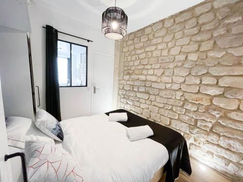 une chambre avec deux lits et un mur en pierre dans l'établissement LE GRACIEUX - MILORA INN - Central Paris, à Paris