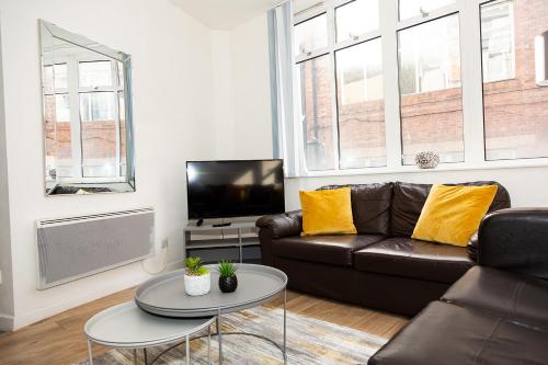 a living room with a leather couch and a tv at Alexander Apartments Powdene House in Newcastle upon Tyne