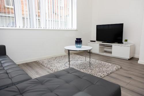 uma sala de estar com um sofá, uma mesa e uma televisão em Alexander Apartments Powdene House em Newcastle upon Tyne
