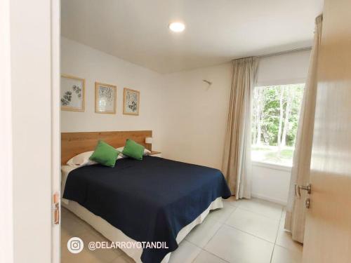 um quarto com uma cama com almofadas verdes e uma janela em Del arroyo Tandil em Tandil