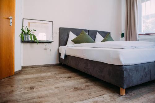 a bedroom with a large bed with white sheets and green pillows at Hotel Restaurant Nöth in Hammelburg
