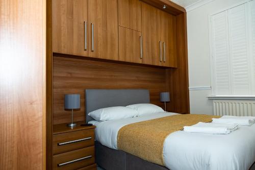 een slaapkamer met een groot bed en houten kasten bij Alexander Apartments Blyth in Cowpen