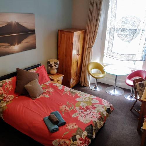 a bedroom with a red bed and a table and a window at aabAlree Guest House in Dundee
