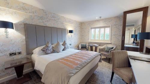 a bedroom with a large bed and a desk and chair at Grosvenor Pulford Hotel & Spa in Pulford
