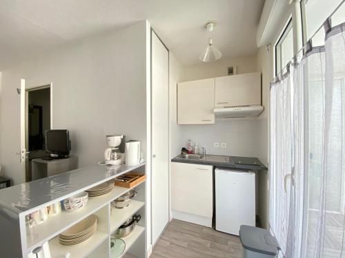 une cuisine avec des armoires blanches et un comptoir dans l'établissement Joli studio avec terrasse près du vieux-port, à La Rochelle