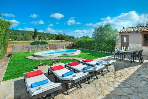 patio con sedie, tavolo e piscina di Owl Booking Villa Garreta - Rustic Stay with Mountain Views a Campanet