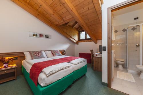een slaapkamer met een groot bed en een badkamer bij Cadria Nature & Bike Hotel in Lenzumo di Concei