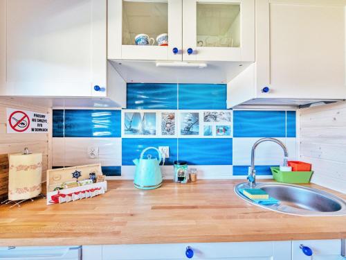 een keuken met blauwe en witte kasten en een wastafel bij Linowe Domki - domki letniskowe nad morzem in Rusinowo