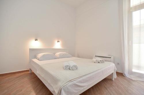 a white bedroom with a bed with two towels on it at Victoria Center Apartments in Budva