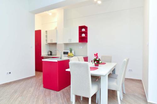 a kitchen with a table with white chairs and red cabinets at Victoria Center Apartments in Budva