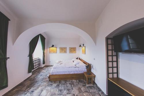 a bedroom with a bed and a flat screen tv at Penzion Šatlava in Nové Město nad Metují