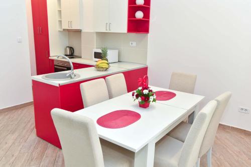 a kitchen with a white table and white chairs at Victoria Center Apartments in Budva