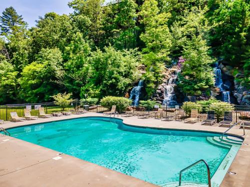 a swimming pool with chairs and a waterfall at Getaway Cabin, 360 Deck, Theater, HotTub, Mins to PF in Sevierville