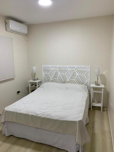 ein Schlafzimmer mit einem weißen Bett und zwei Nachttischen in der Unterkunft Monoambiente Plaza Belgrano in San Miguel de Tucumán