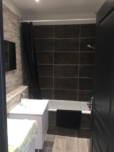 a bathroom with a white sink and a bath tub at Le coin des Halles dans le vignoble de Bourgueil in Bourgueil