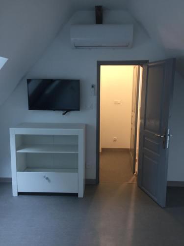 - un salon avec une télévision et une commode blanche dans l'établissement Le coin des Halles dans le vignoble de Bourgueil, à Bourgueil