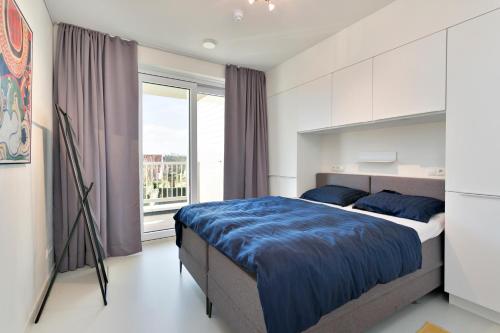 een slaapkamer met een bed en een groot raam bij Modern appartement met doorkijk op de duinen in Cadzand