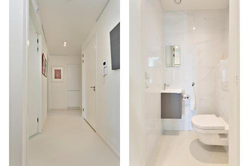 a white bathroom with a toilet and a sink at Modern appartement met doorkijk op de duinen in Cadzand