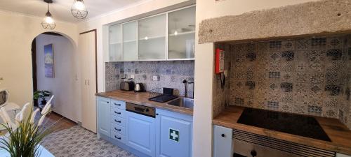 una cocina con armarios blancos y fregadero en Casa do Alfaiate ® Home&Breakfast en Almada