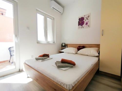 a bedroom with a bed with white sheets and a window at Apartmani Buljubašić in Baška Voda
