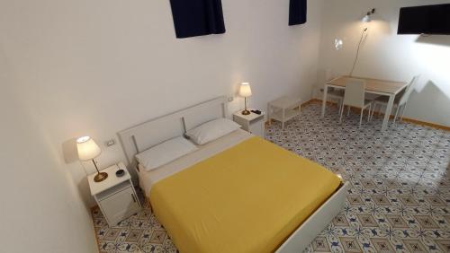 Un dormitorio con una gran cama amarilla y un escritorio en Villa Mary - Apartments, en Trani