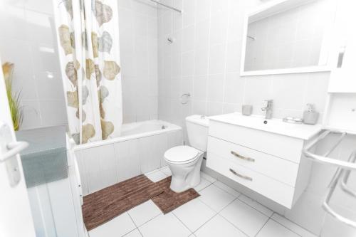 a white bathroom with a toilet and a sink at Appartement à 700m gare centrale/plage in Pointe-Noire