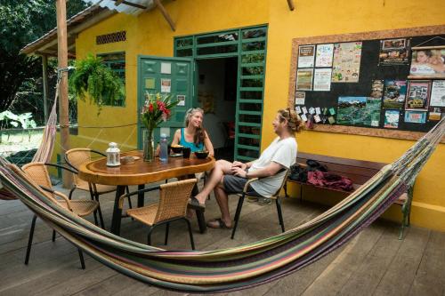 two women sitting in a hammock outside a restaurant at Finca Hostal Bolivar - Casa Maracuya in Minca
