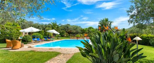 a swimming pool in a yard with chairs and umbrellas at Villa Luna Smeralda ad Alghero villa con piscina ad uso esclusivo per 8 persone in Alghero