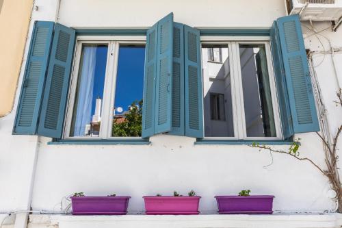 a window with blue shutters on a white building with plants at Yiayia's guesthouse in Skopelos Town
